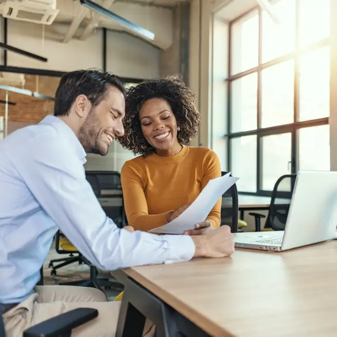 Un homme et une femme discutent d'un document dans un bureau